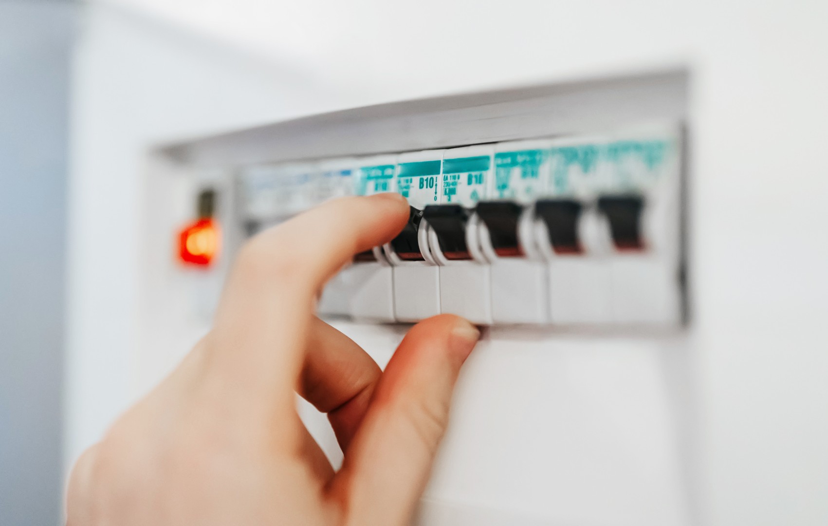 Male hand switching on fuse board.